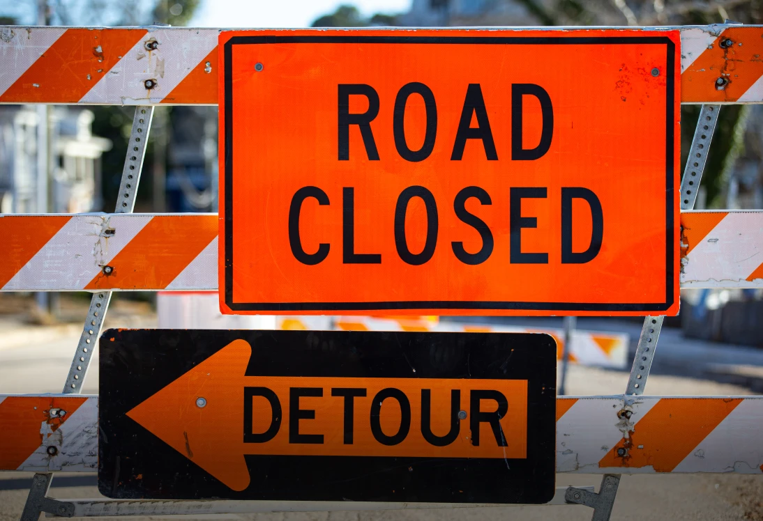 Orange road closure barricade and detour sign